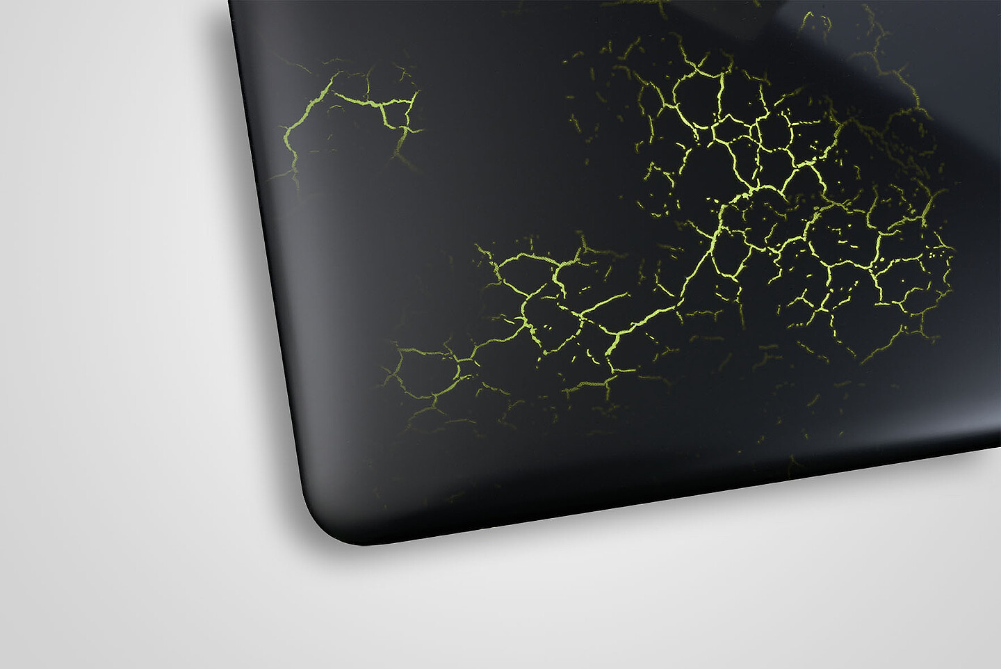 schwarzer Laptop-Deckel mit grüner hinterleuchteter Struktur, die aussieht wie Sprünge in der Oberfläche